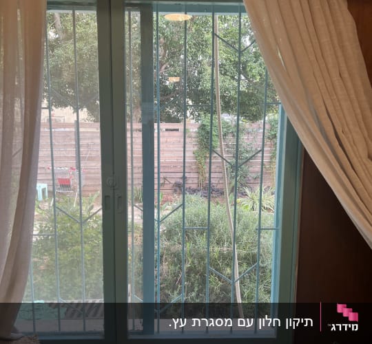 חלון זכוכית עם סורגים ווילונות לבנים